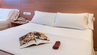 a book laying on top of a bed with a phone at Hotel Alba in Puzol