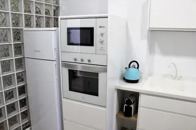 a white kitchen with a refrigerator and a sink at Playa Cabañyal - Diseño Mediterraneo in Valencia
