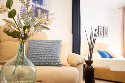 a glass vase with flowers on a table next to a couch at LObjet trouvé in Valencia