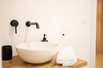 a bathroom with a white bowl sink on a wooden counter at LObjet trouvé in Valencia