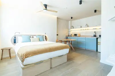 a bedroom with a large bed and a kitchen at Nomad HAUX Puerto in Valencia
