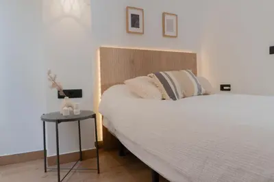 a bedroom with a large bed and a side table at Stylish downtown charm in Valencia