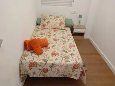 a small bedroom with a bed with a floral bedspread at Apartament El Colomer 3 habitacions in Simat de Valldigna