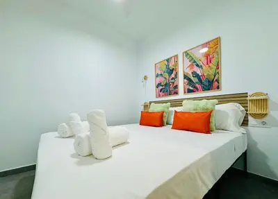 a bedroom with a large white bed with colorful pillows at Cute & Cozy Aparment Near The Historic Center in Valencia