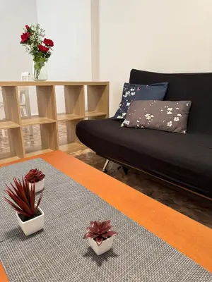 a living room with a bed and a table with flowers at Escapate con estilo en Valencia in Valencia