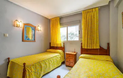a bedroom with two beds and a window with yellow curtains at Lovely Apartment In Faro De Cullera in Faro de Cullera