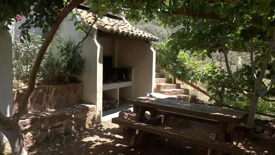 a wooden picnic table in a garden with a bench at Les Eres de Gátova in Gátova