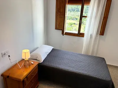 a bedroom with a bed with a nightstand and a window at Your stylish retreat in Sierra Espadán in Vall de Almonacid