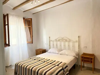 a bedroom with a bed with a striped blanket and a window at Your stylish retreat in Sierra Espadán in Vall de Almonacid