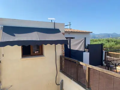 a building with a blue awning on a balcony at La Terreta hotel casa rural in El Brosquil
