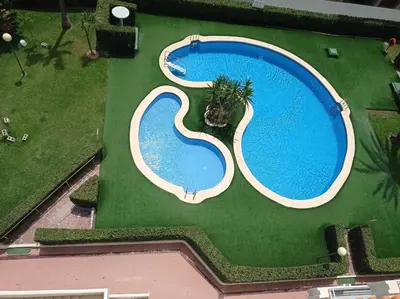 an overhead view of a swimming pool on a green field at Perla III Solo Familias Serviplaya in Casas Las Basas