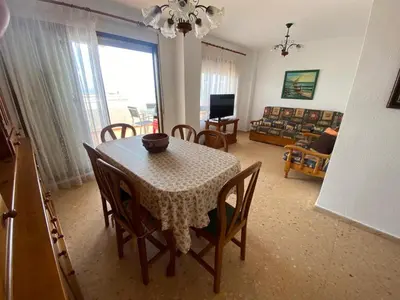 a dining room with a table and chairs and a living room at Perla III Solo Familias Serviplaya in Casas Las Basas