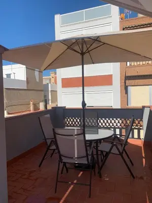 a table and chairs under an umbrella on a balcony at Apartamento El Atardecer in El Perelló