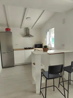 a white kitchen with two chairs and a counter at Chalet con piscina dogfriendly in Algar de Palancia