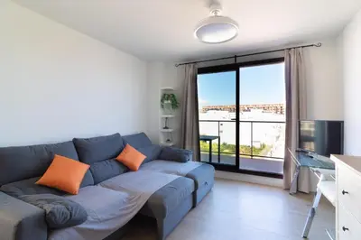 a living room with a blue couch and a large window at Global Vacacional, Apartamento con piscina en Puerto de Sagunto in Puerto de Sagunto