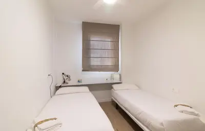 two beds in a white room with a window at Global Vacacional, Apartamento con piscina en Puerto de Sagunto in Puerto de Sagunto