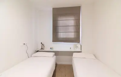 two beds in a white room with a window at Global Vacacional, Apartamento con piscina en Puerto de Sagunto in Puerto de Sagunto
