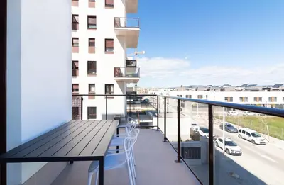 a balcony with a table and a view of a city at Global Vacacional, Apartamento con piscina en Puerto de Sagunto in Puerto de Sagunto