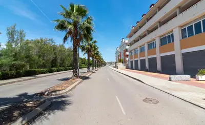 an empty street with palm trees and a building at Global Vacacional, Planta baja con piscina en Almenara in Almenara