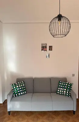 a living room with a gray couch and a chandelier at Ático en el centro con terraza in Valencia