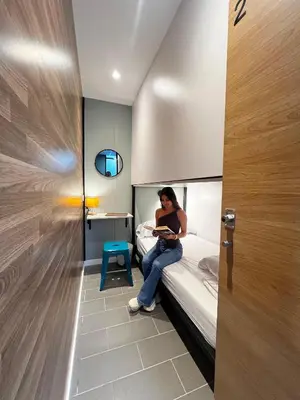 a woman sitting on a bed reading a book at U-nit Hostel Central Park in Valencia