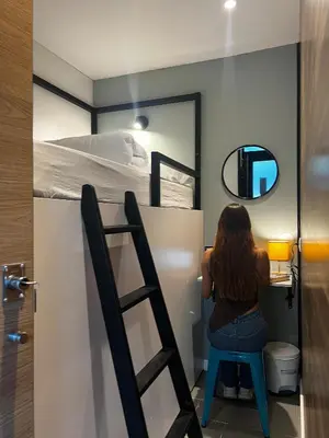 a woman sitting on a stool in front of a bunk bed at U-nit Hostel Central Park in Valencia