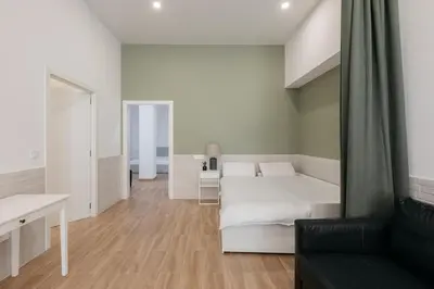 a bedroom with a white bed and a black couch at New! Comfort and Style Steps from Everything in Valencia