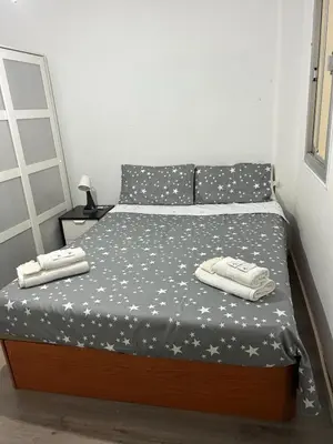 a bed with a black and white comforter with towels on it at Habitación En Benicalap in Valencia