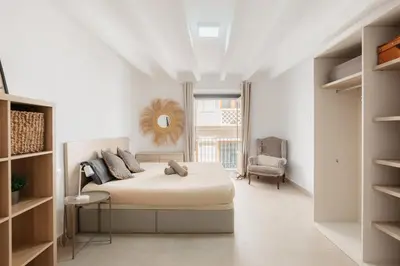 a white bedroom with a bed and a chair at Comfort & Charm in the Center in Valencia