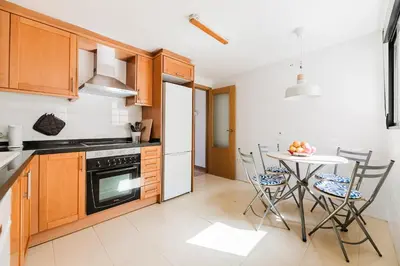 a kitchen with wooden cabinets and a table with chairs at Urban Oasis near the beach in Puerto de Sagunto