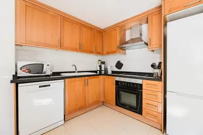 a kitchen with wooden cabinets and a white appliance at Urban Oasis near the beach in Puerto de Sagunto