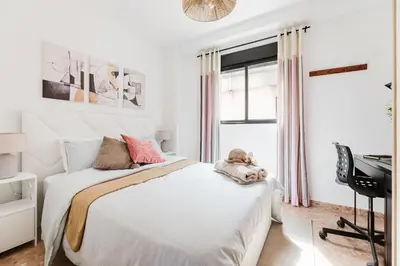 a white bedroom with a bed and a desk at Urban Oasis near the beach in Puerto de Sagunto
