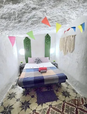 a bedroom with a bed with colorful flags on the ceiling at Casa Cueva Puerta Verde in Paterna