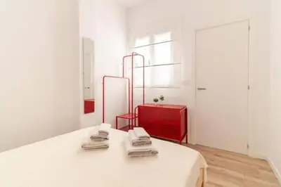 a white room with a bed and a red suitcase at Super Apto 2habitaciones dobles 4 pax wifi terraza in Valencia
