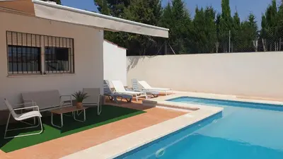 a swimming pool with chairs and a table next to a house at Villa a un paso de Valencia in Riba-Roja De Turia