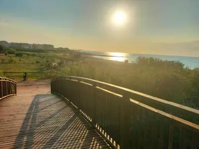 a boardwalk with the sun rising over the ocean at Apartamento en playa de Moncofar con wifi y aire acondicionado in Moncófar