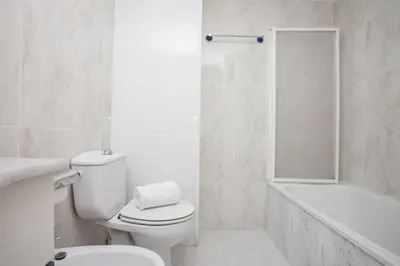 a white bathroom with a toilet and a bath tub at Apartments Serrería II in Valencia