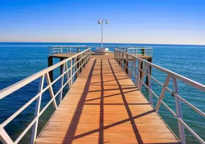 a wooden pier over the water with a light on it at Dúplex tranquilo frente al mar en Xilxes Terraza, parking y WiFi in Chilches