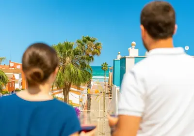 a man and a woman looking out at the beach at Dúplex tranquilo frente al mar en Xilxes Terraza, parking y WiFi in Chilches