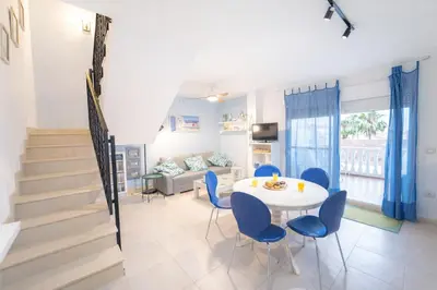 a living room with a white table and blue chairs at Dúplex tranquilo frente al mar en Xilxes Terraza, parking y WiFi in Chilches