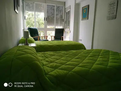 a bedroom with two green beds with chairs and a window at EL Cid II in Valencia