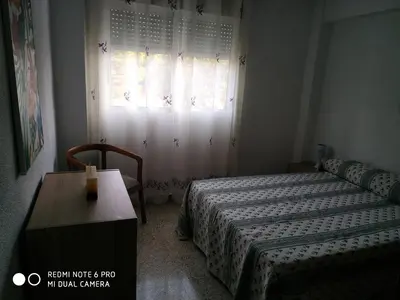 a bedroom with two beds and a table and a window at EL Cid II in Valencia