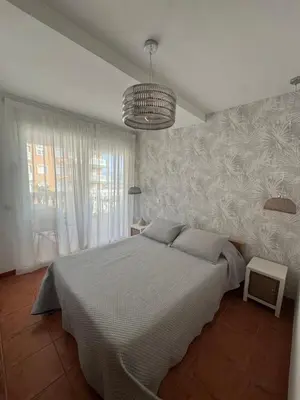 a bedroom with a large bed and a chandelier at Gaviota Azul, Perelló in Sueca