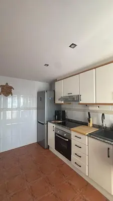 a kitchen with white cabinets and black appliances at Gaviota Azul, Perelló in Sueca