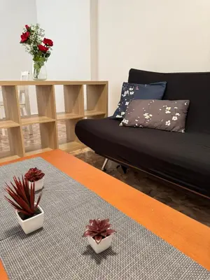 a living room with a bed and a table with flowers at Sweet Stay Valencia in Valencia