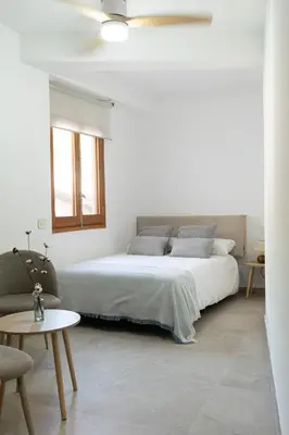 a white bedroom with a bed and a chair at Aromes d'Espadà in Eslida