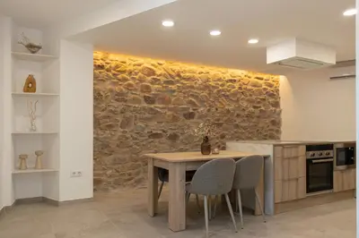 a kitchen with a table and a stone wall at Aromes d'Espadà in Eslida