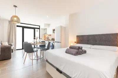 a bedroom with a large bed and a kitchen at Suite Deluxe Valencia - Beach Apartments I in Valencia