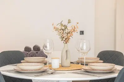 a table with plates and glasses and a vase at Suite Deluxe Valencia - Beach Apartments I in Valencia