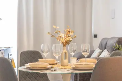 a table with plates and glasses and a vase with flowers at Suite Deluxe Valencia - Beach II Apartments in Valencia